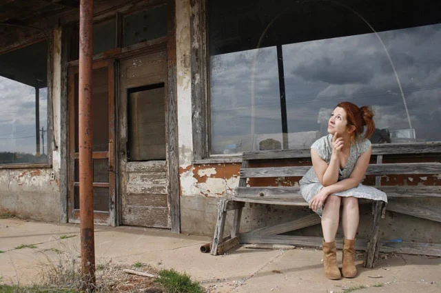 Lia sitting outside a rustic building