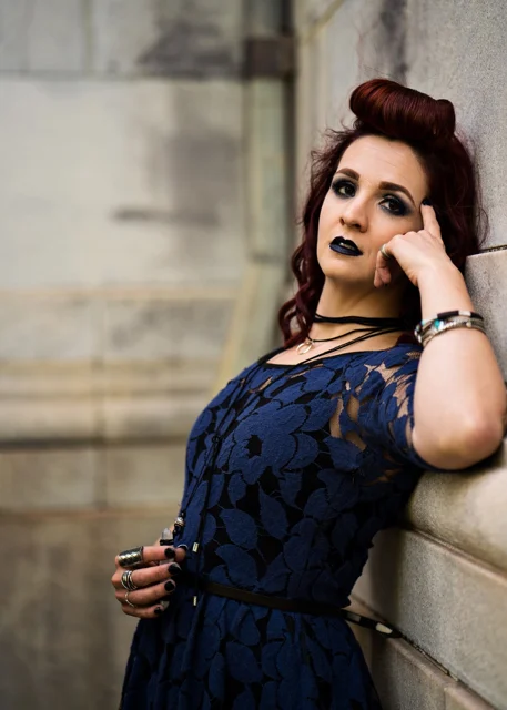 Lia in a blue dress beside a wall
