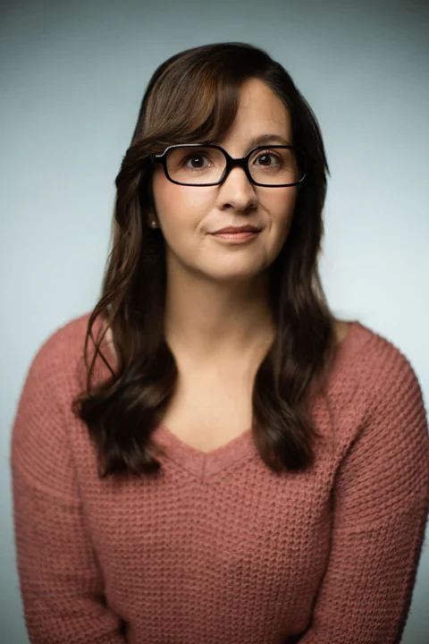 Lia in glasses and a rose sweater