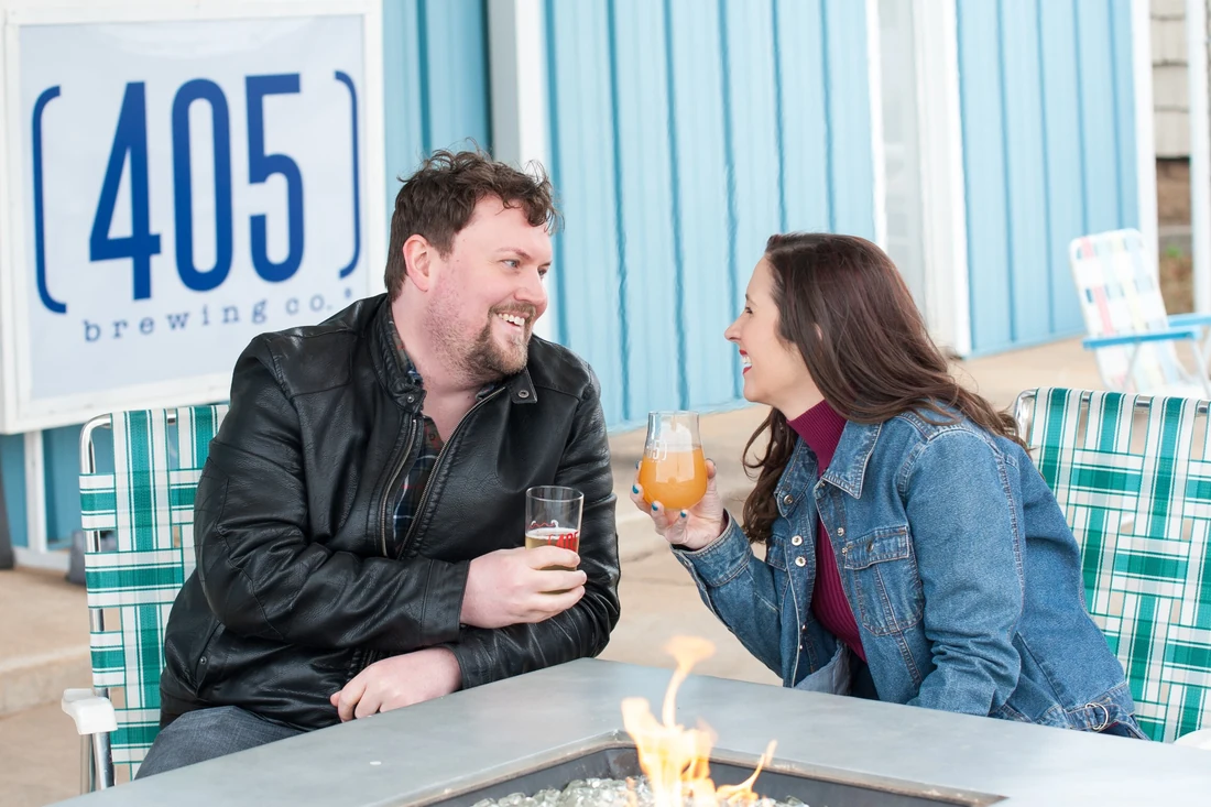 Lia chatting with another model beside an outdoor fire table at 405 Brewing